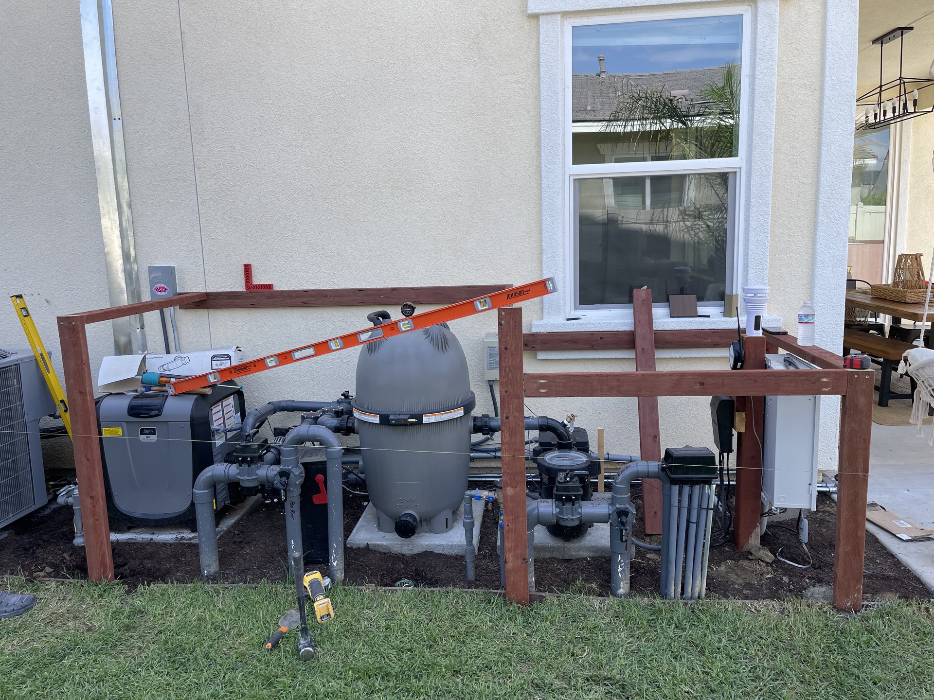 Pool equipment exposed against the house wall — before